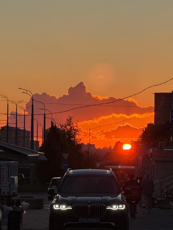 Kazan street at golden hour, dark SUV under a fiery sky