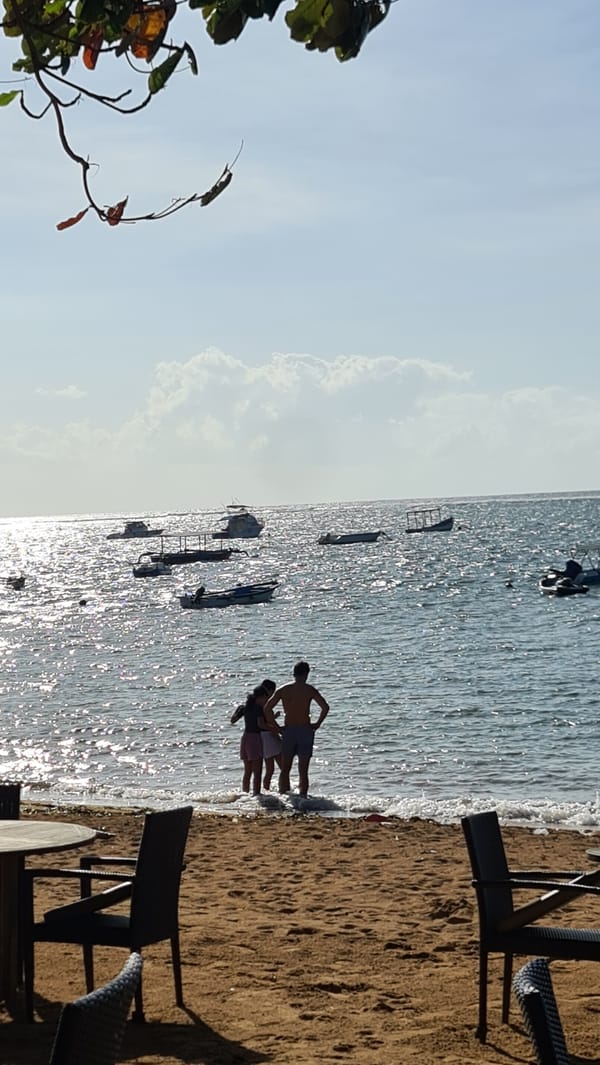 Sunny afternoon at Seminyak beach — jetty, boats, and shoreline.