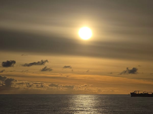 Ocean sunset observed with ship on horizon