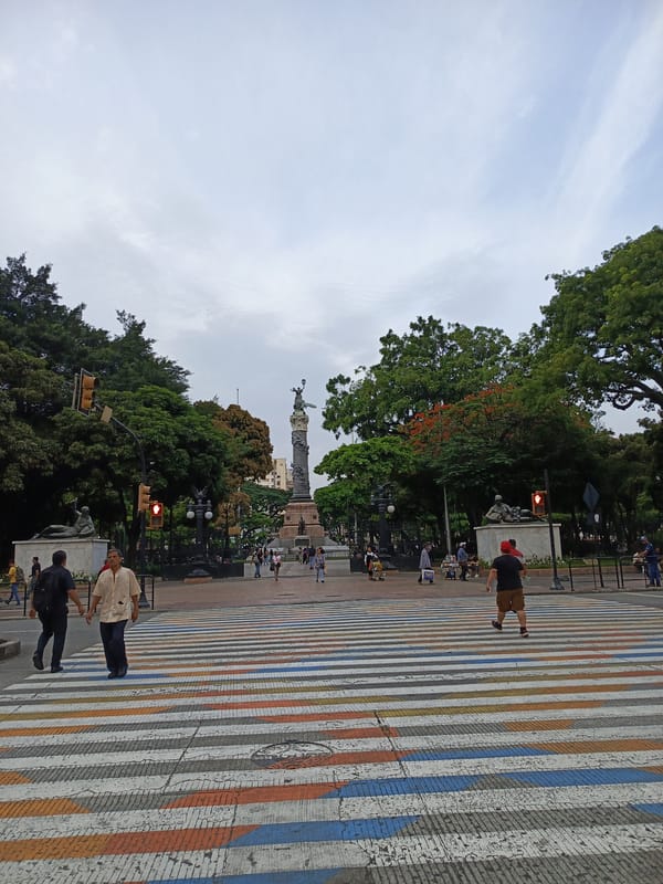Evening pedestrians cross colorful crosswalk near Guayaquil monuments