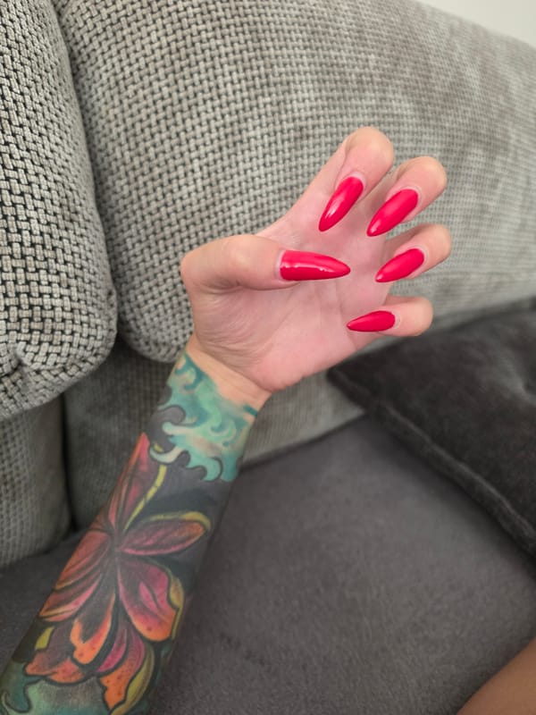 Red nails, Elsa dolls, and a tattoo on a grey couch
