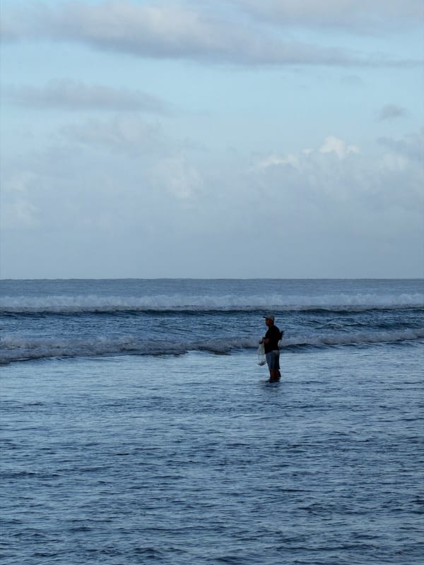 Person explores rocky coastline during low tide in Kuta Selatan