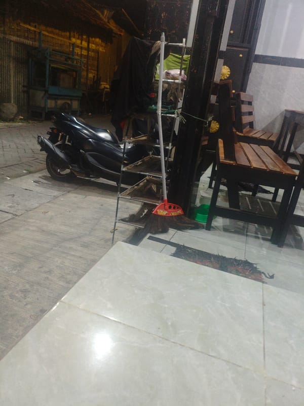 Scooter parked on Surabaya sidewalk with cleaning equipment nearby
