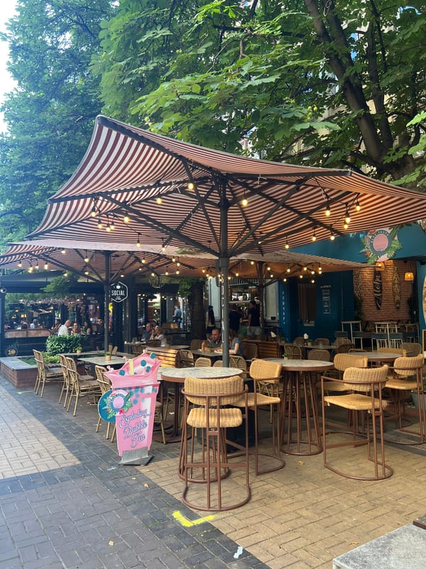Busy outdoor cafe terrace with striped awning in Sofia