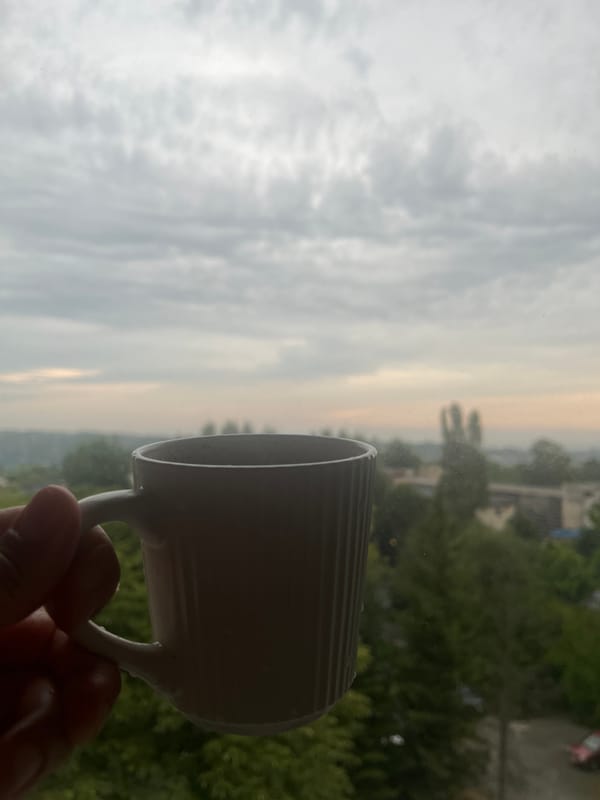 City skyline views from a window, cloudy day, mug in hand