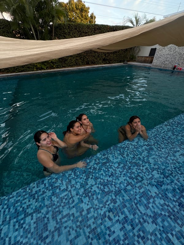Three women swim in green-water pool in Puerto Escondido