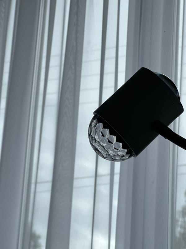 Black desk lamp with faceted dome bulb observed near blinds
