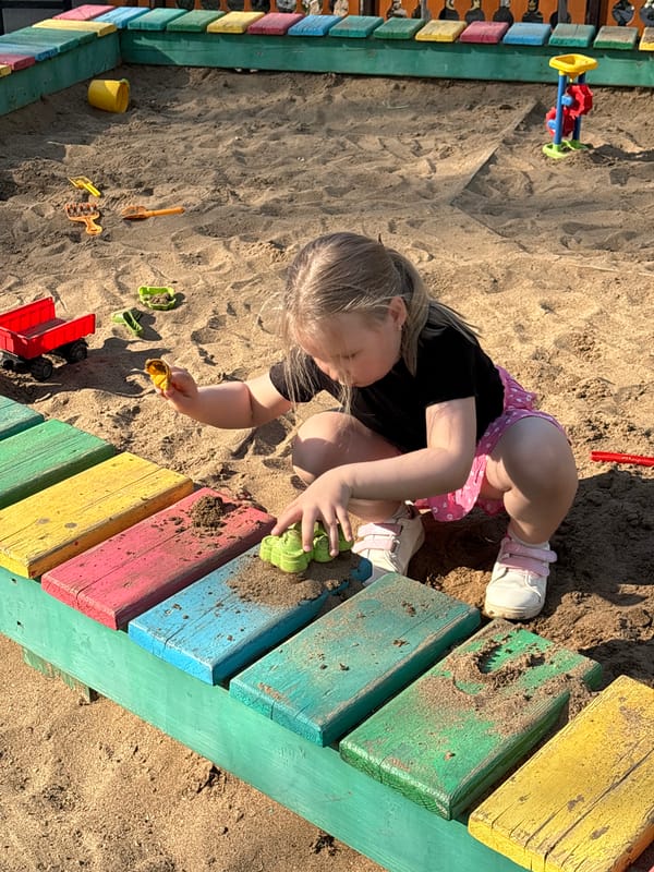 Child plays in sandbox with toys