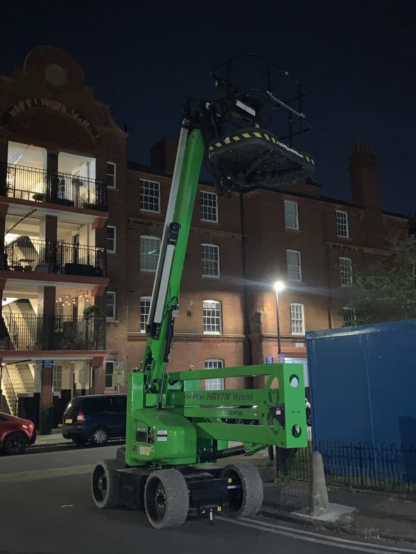 Green aerial work platform spotted in London nighttime scene