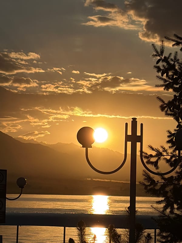 Golden hour sunset over mountain-backed water from a pier