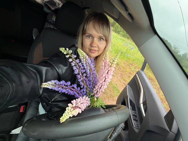 Woman poses with lupine flowers in car during Chaikovsky morning