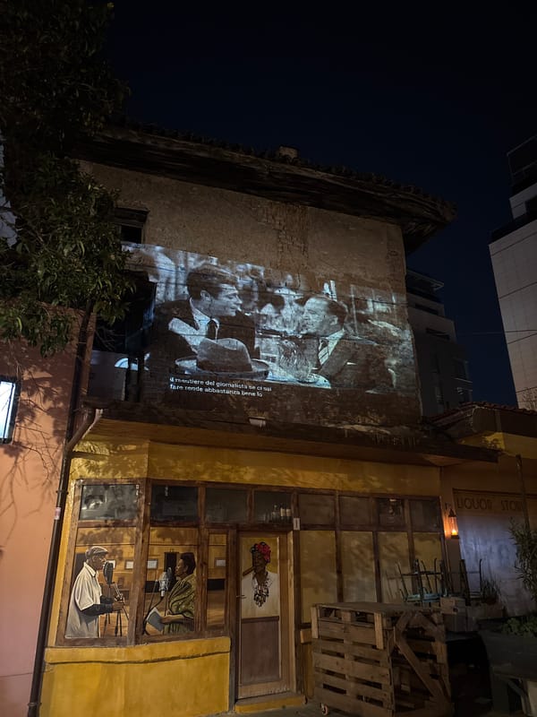 Traditional drummer performs in Tirana square near colorful mural