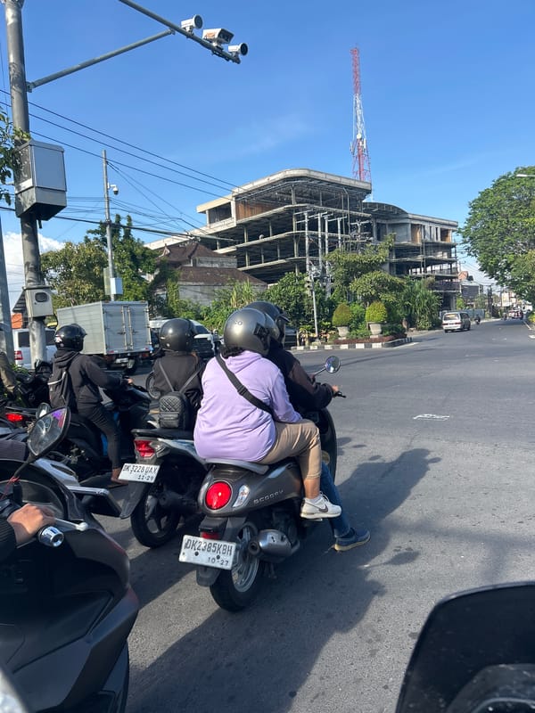 Midday traffic at a Denpasar intersection, police presence included