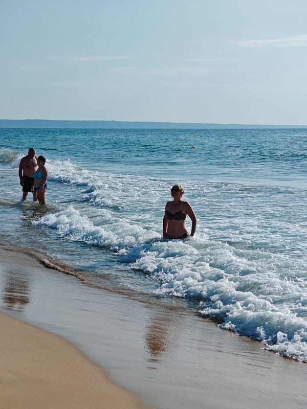Calm beach day: wading, stretching, and clear blue water