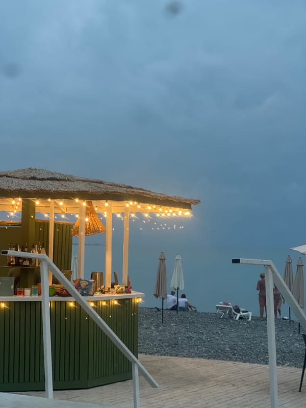 Thatched beach bar glows at dusk on Sokhumi's Black Sea coast
