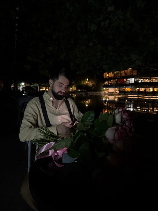 Man holds rose bouquet outdoors in Yerevan night scene