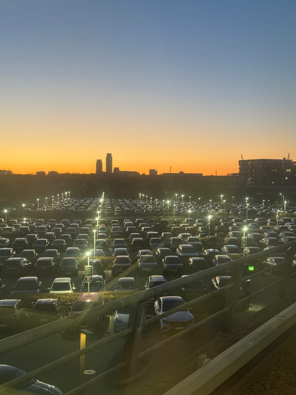 Automated train passes Copenhagen car lot during twilight hours