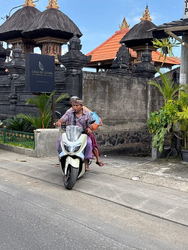 Two people travel by scooter in Mengwi, Indonesia