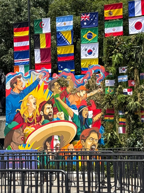 Public art, flags, and skyline along a Mexico City street