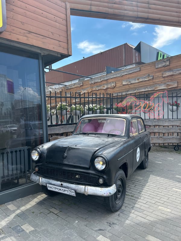 Black vintage car with chrome bumper parked on cobblestone sidewalk