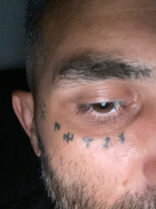 Close-up details of small facial tattoos and symbols