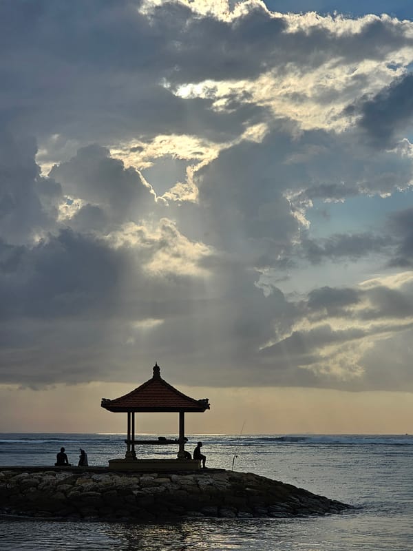 Dusk gathering on Sanur Beach's rocky coastal embankment