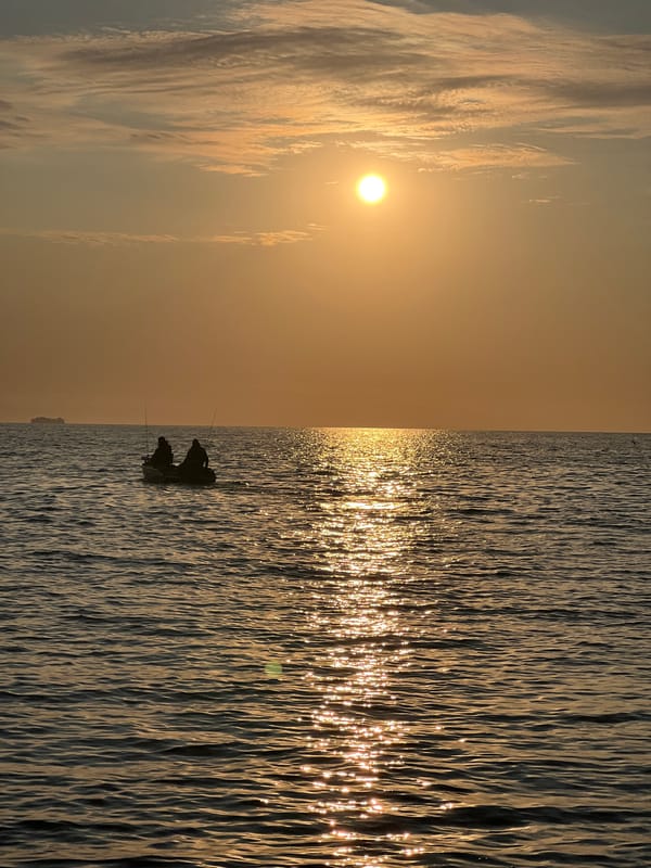 Inflatable boat pulled ashore at sunset, lakeside camp set up