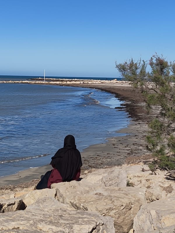 Person in hijab enjoys quiet moment on Dénia beach