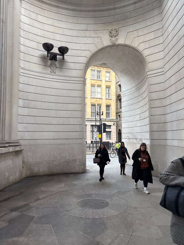 Pedestrians navigate historic archway near London's Bank Station