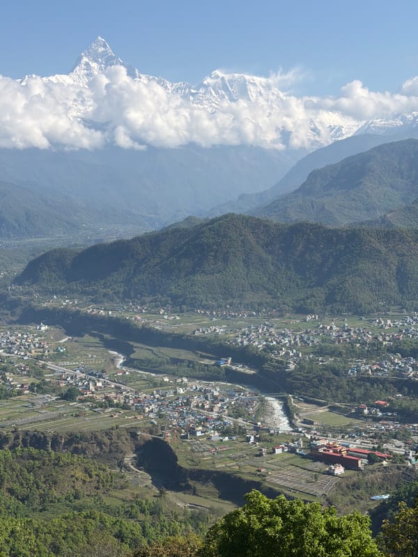 Two pedestrians walk curved road near Pokhara, Nepal
