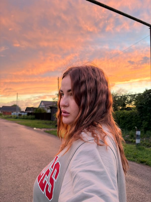 Woman photographed on urban street during sunset hours