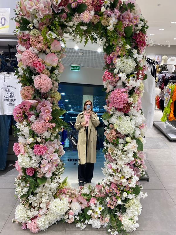 Person in trench coat reflected in flower-adorned mirror, Yekaterinburg