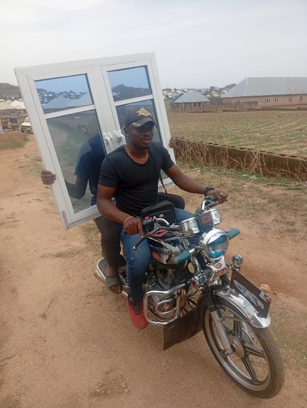 Motorcycle passenger carries large blue window through Jos, Nigeria