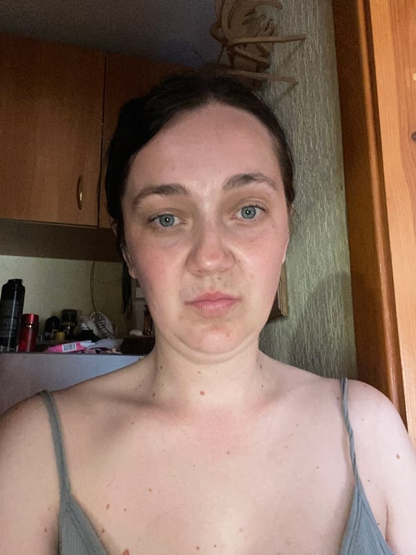 Close-up portrait shot, neutral expression, hair pulled back