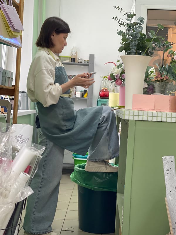 Woman arranges flowers, takes photos at flower shop