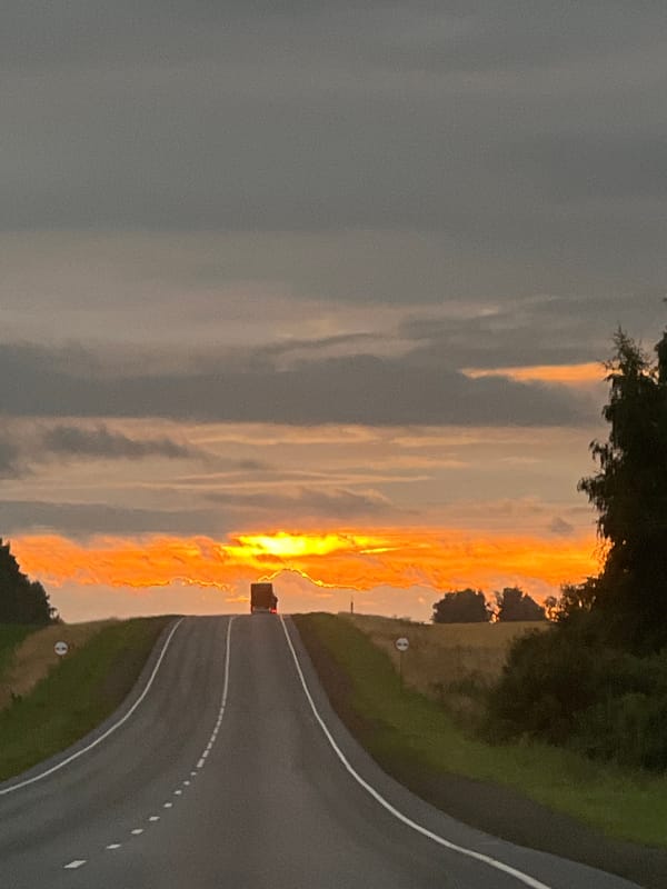 Dusk drive on a rural Russian highway under a fiery sunset