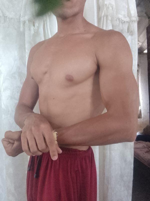 Man flexes arms indoors in Juan Griego, Venezuela