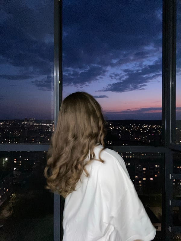 Woman takes selfies at window during sunset in Izhevsk