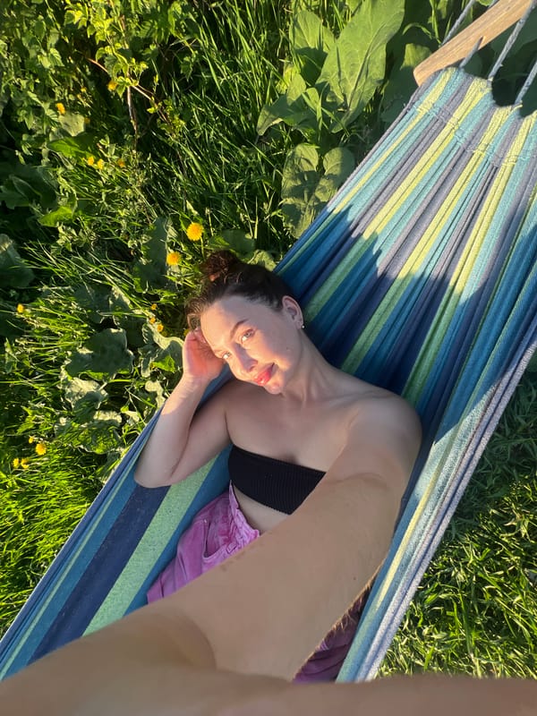 Woman relaxes in hammock amid dandelions in Chaikovsky, Russia