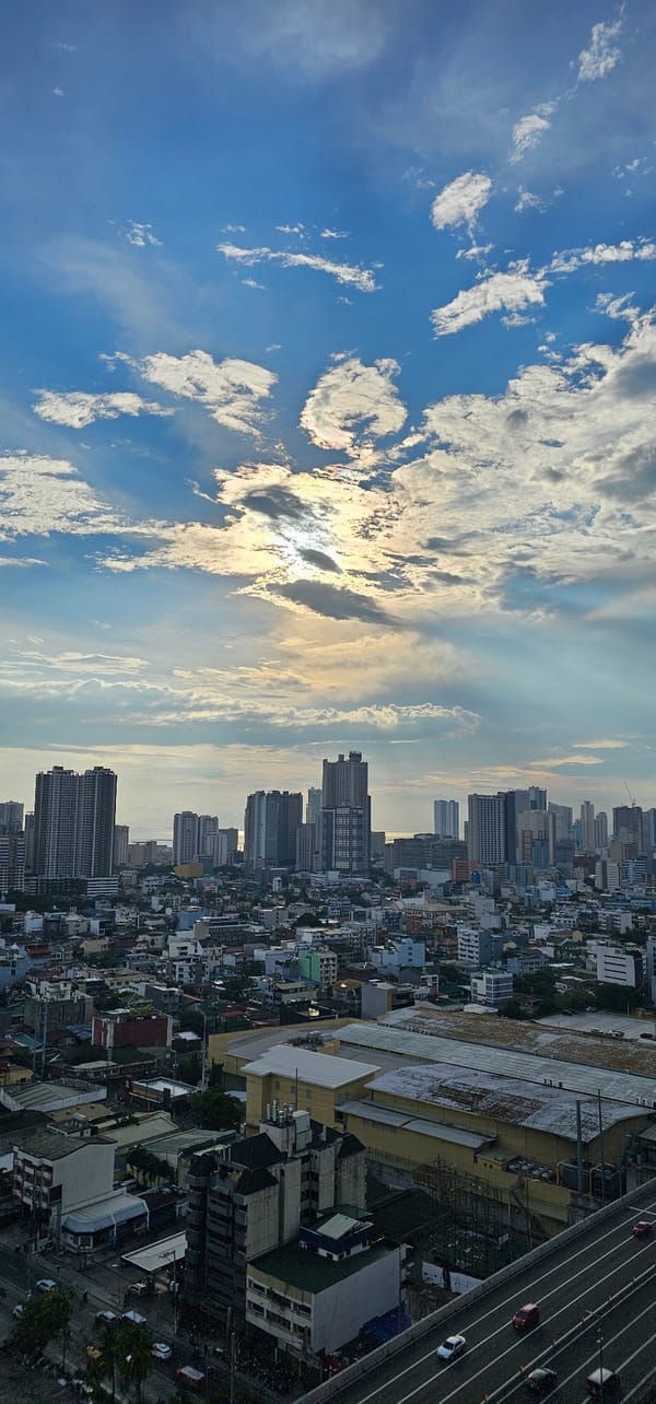 Makati skyline from above, city sprawl under cumulus clouds