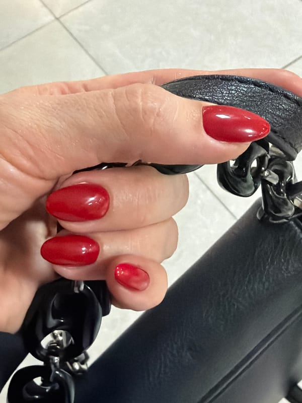 Person with red nails holds decorative leather strap in Ukraine