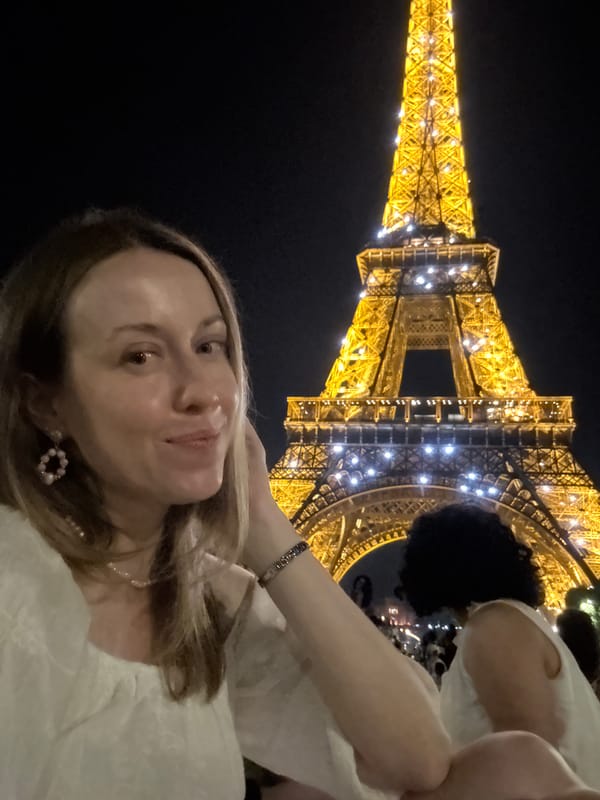Eiffel Tower lit up at night, crowds gathered below