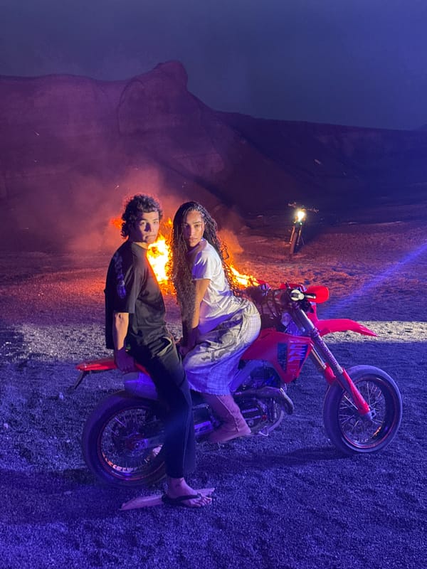 Two people pose on dirt bike near fire in Teguise