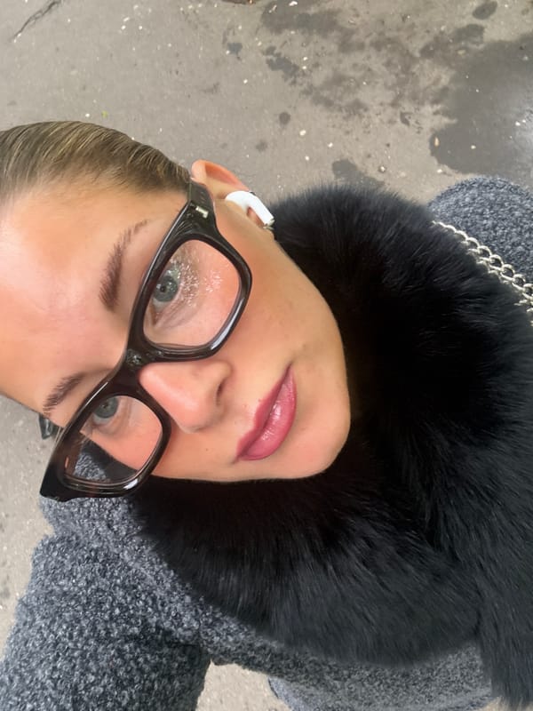 Woman takes selfies in Paris wearing glasses and earbuds
