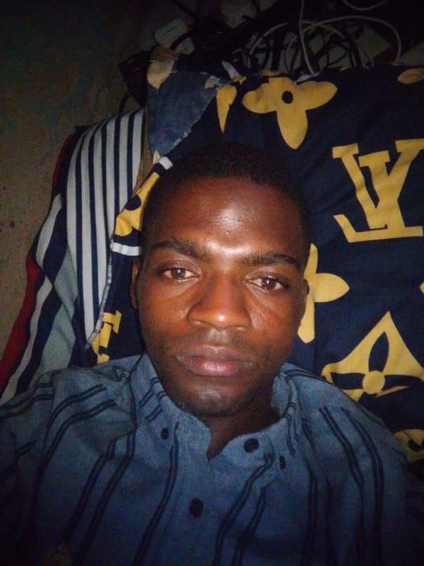 Man rests on bed with mismatched sheets in Abuja