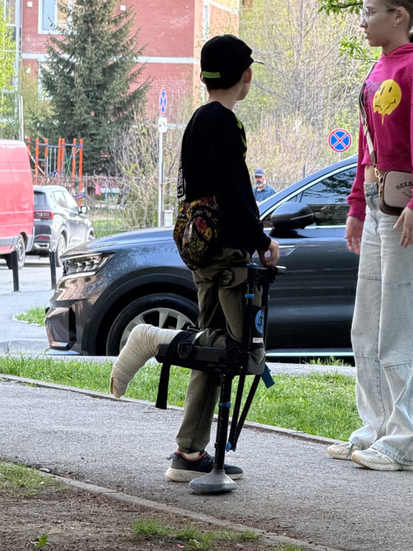 Children play on Yekaterinburg sidewalk, person with cast observed