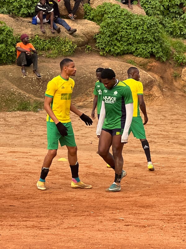 Informal soccer match on a rocky dirt pitch in Jos, Nigeria