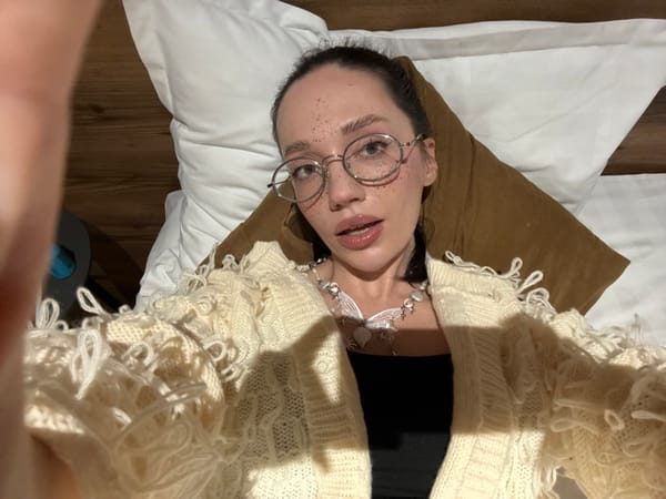 Woman rests in bed wearing butterfly necklace in Yerevan