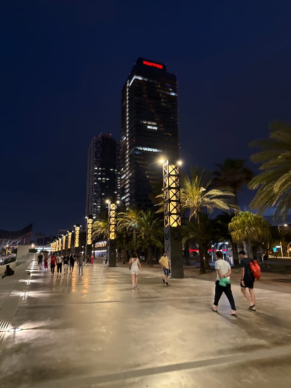 Evening crowds stroll Barcelona's lit beachfront promenade