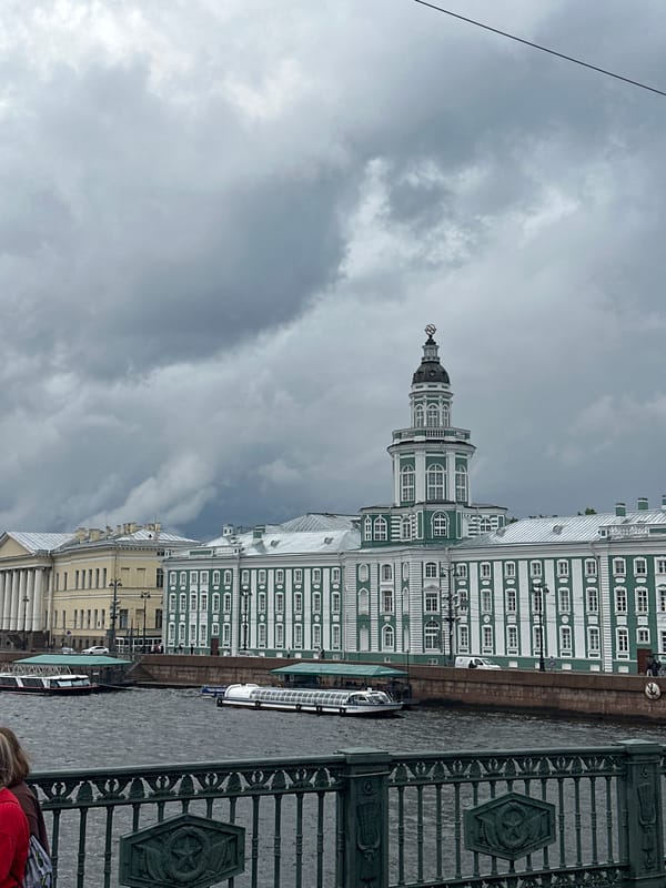 Green and white riverside building under overcast urban skies
